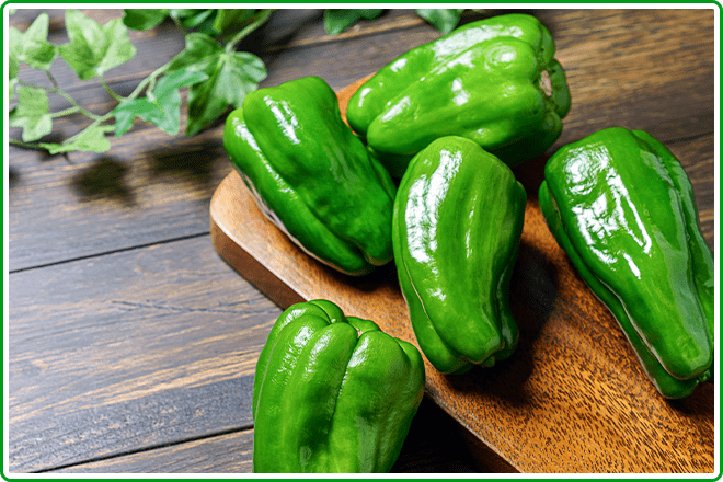 木目の机におかれたピーマンの画像